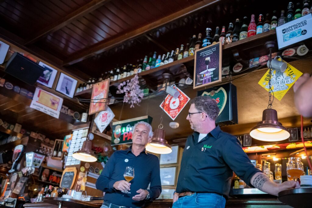 Twee prominente gasten tijdens een bier-event in een bruin café in Twente. Brouwer Marc Janssen van Grolsch in gesprek met voetbaltrainer Fred Rutten, samen genietend van mooi bier