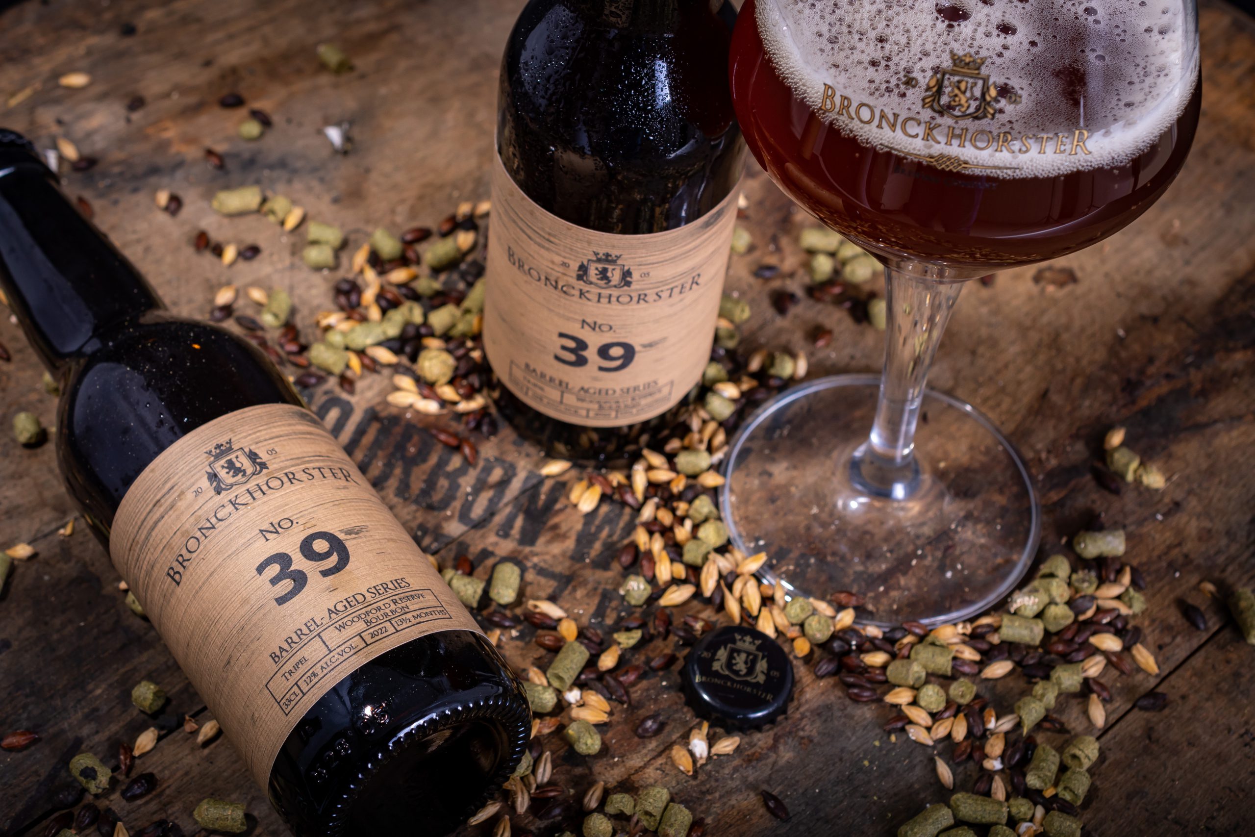 Sfeervolle productfoto van ambachtelijk gebrouwen bier met hop-pellets, verschillende mouten gepositioneerd op een bourbon-vat