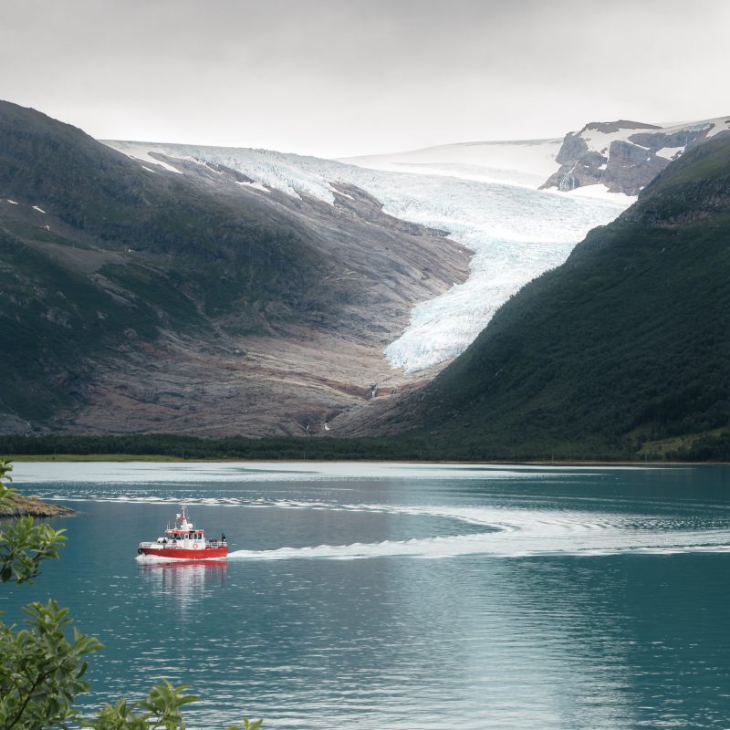 Rode boot op een Noord Noors gletsjermeer onder een dreigende grauwe lucht